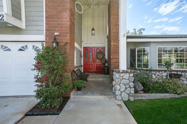 view of exterior entry featuring a garage and brick siding