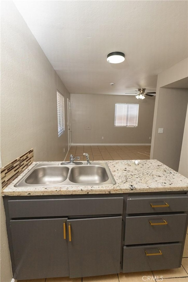 kitchen with ceiling fan, gray cabinets, light countertops, and a sink