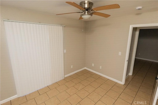 unfurnished room featuring ceiling fan, baseboards, and light tile patterned flooring