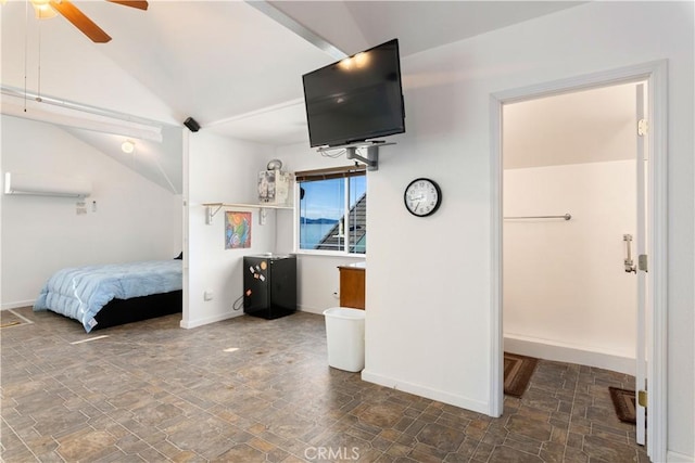 bedroom with lofted ceiling, stone finish flooring, and baseboards