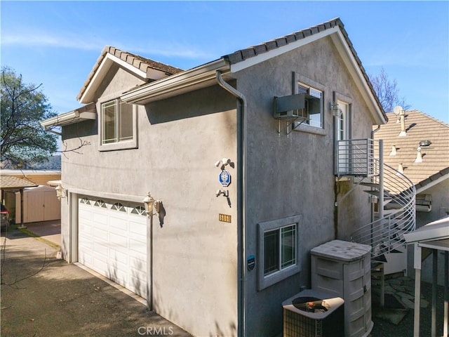 view of side of home with a garage, central AC unit, and stucco siding