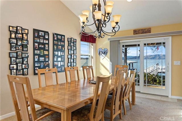 dining area with light carpet, light tile patterned floors, baseboards, a water view, and an inviting chandelier