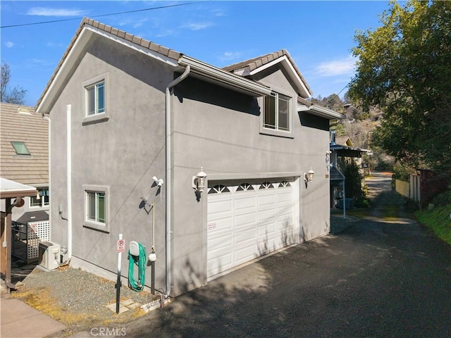 view of side of home featuring a garage and stucco siding