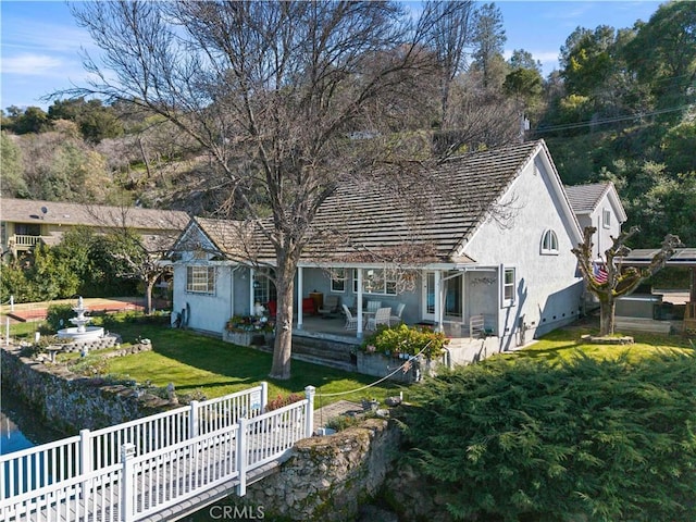 view of front of house with a patio, a front lawn, fence, and stucco siding