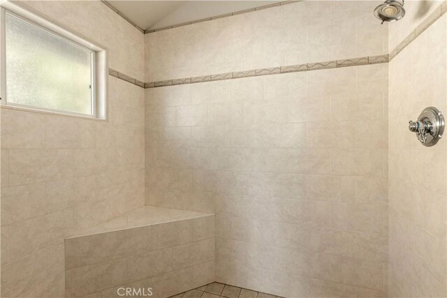 bathroom featuring lofted ceiling and a tile shower