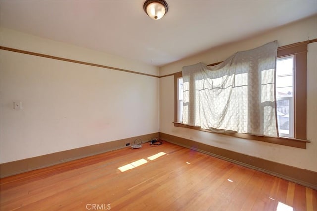 unfurnished room with wood-type flooring and baseboards