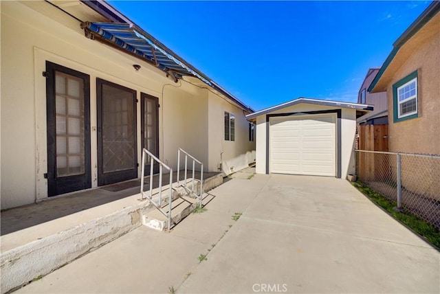 exterior space featuring a garage, fence, driveway, and an outdoor structure