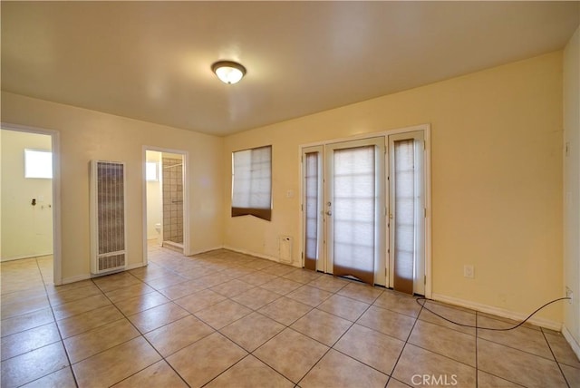 empty room featuring a heating unit, baseboards, and light tile patterned floors