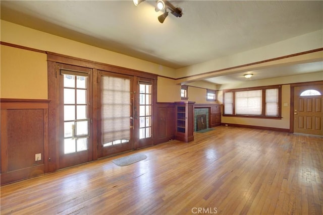 unfurnished living room featuring a wainscoted wall, a fireplace, and hardwood / wood-style floors