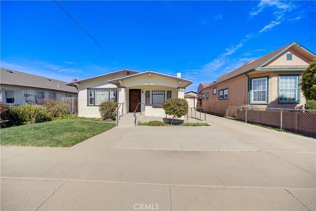 view of front of home with fence, driveway, a front lawn, and stucco siding