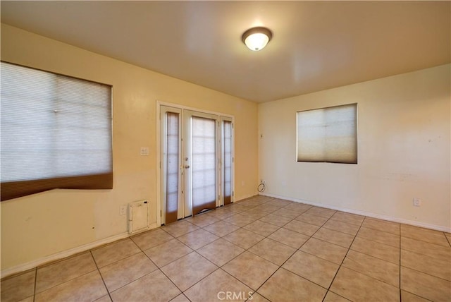 empty room with light tile patterned floors and baseboards