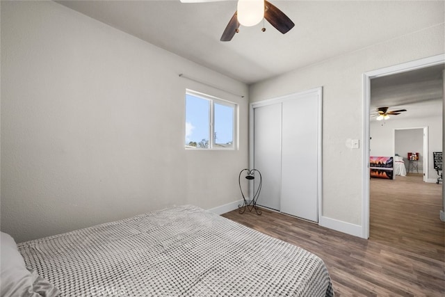 bedroom featuring a ceiling fan, a closet, baseboards, and wood finished floors