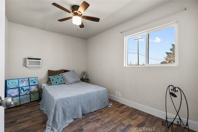 bedroom with a wall unit AC, a ceiling fan, baseboards, and wood finished floors