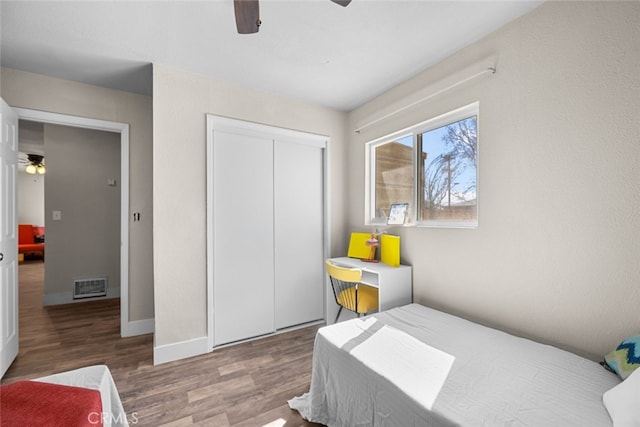 bedroom featuring a closet, visible vents, ceiling fan, wood finished floors, and baseboards