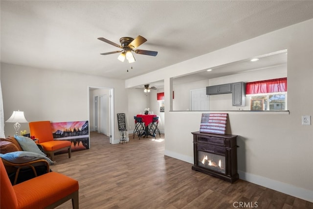 sitting room featuring dark wood-style floors, a textured ceiling, baseboards, and a ceiling fan