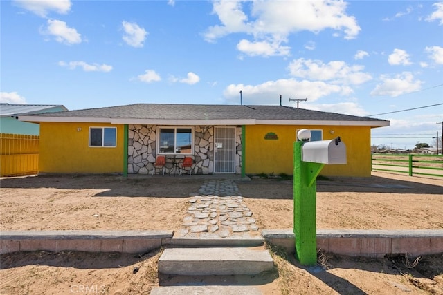 view of front of home with stone siding, fence, and stucco siding