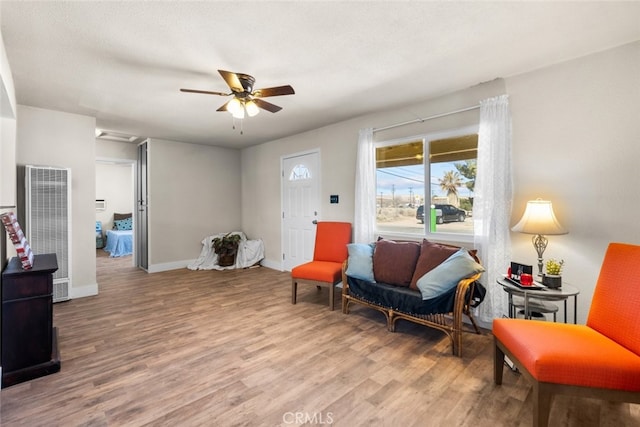 sitting room featuring a heating unit, ceiling fan, a textured ceiling, wood finished floors, and baseboards