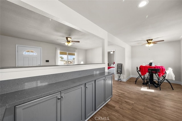 kitchen featuring dark countertops, baseboards, dark wood-type flooring, and gray cabinetry