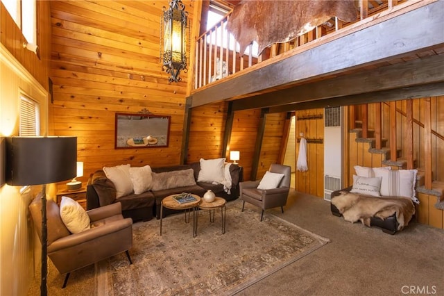 living area featuring carpet floors, stairway, a towering ceiling, and wooden walls