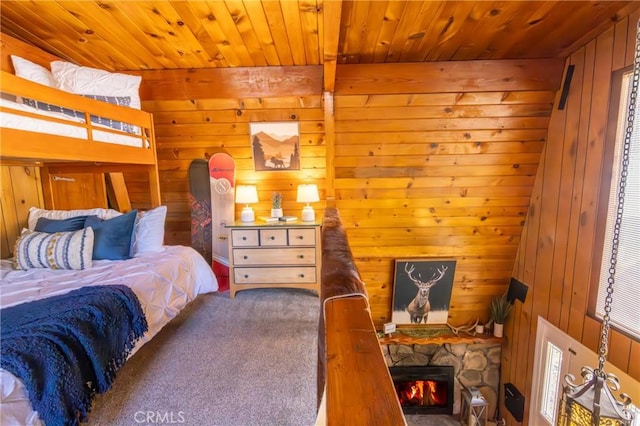 bedroom with wood walls, wood ceiling, and a stone fireplace