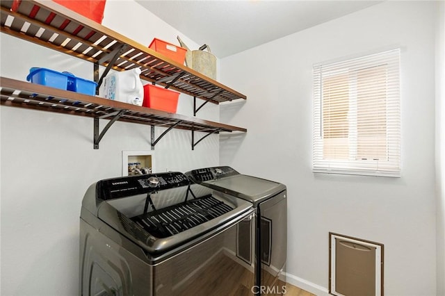 laundry room with laundry area, baseboards, separate washer and dryer, and wood finished floors