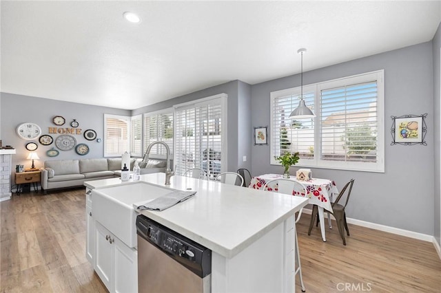 kitchen with white cabinets, a healthy amount of sunlight, light wood-style flooring, and stainless steel dishwasher