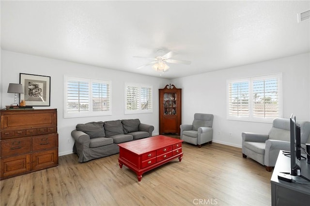 living room featuring a ceiling fan, light wood-type flooring, plenty of natural light, and baseboards