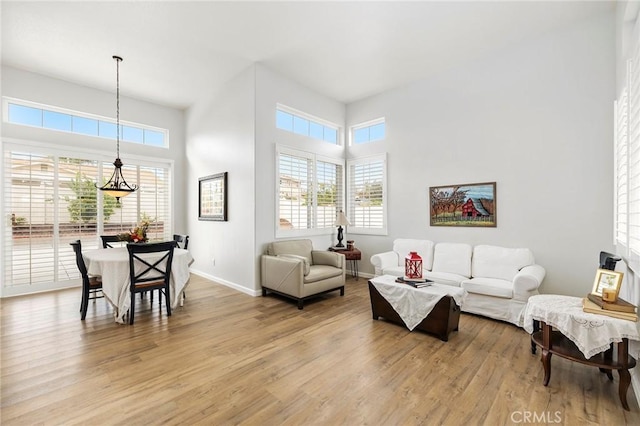 living room with baseboards, a high ceiling, and light wood-style floors