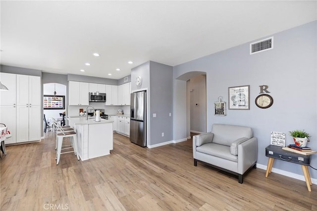 kitchen featuring arched walkways, visible vents, open floor plan, light countertops, and appliances with stainless steel finishes