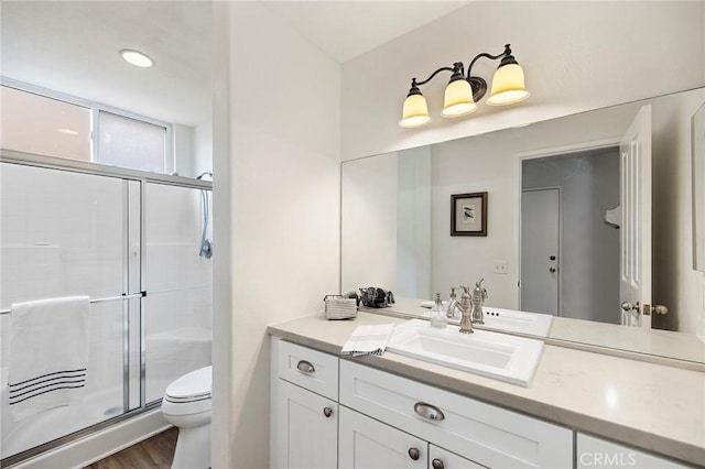 bathroom with a stall shower, vanity, toilet, and wood finished floors