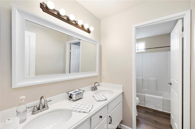 bathroom featuring double vanity, wood finished floors, a sink, and toilet