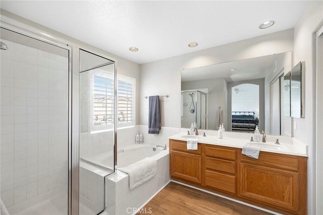 ensuite bathroom with wood finished floors, a sink, a shower stall, and a bath