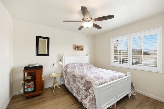 bedroom with ceiling fan, baseboards, and wood finished floors