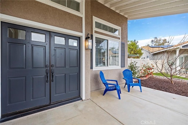 view of exterior entry featuring fence and stucco siding