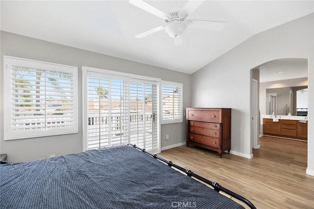 bedroom featuring arched walkways, light wood-style floors, vaulted ceiling, ceiling fan, and baseboards