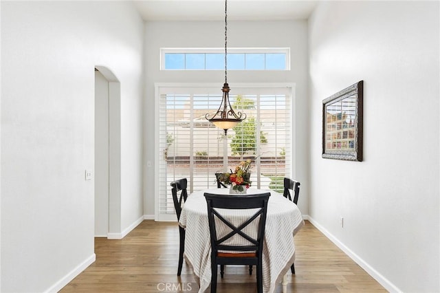 dining area with arched walkways, wood finished floors, and baseboards