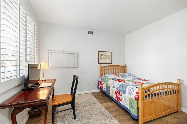 bedroom featuring visible vents, baseboards, and wood finished floors