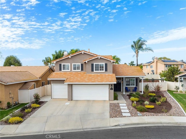 tri-level home featuring stucco siding, concrete driveway, an attached garage, fence, and a tiled roof