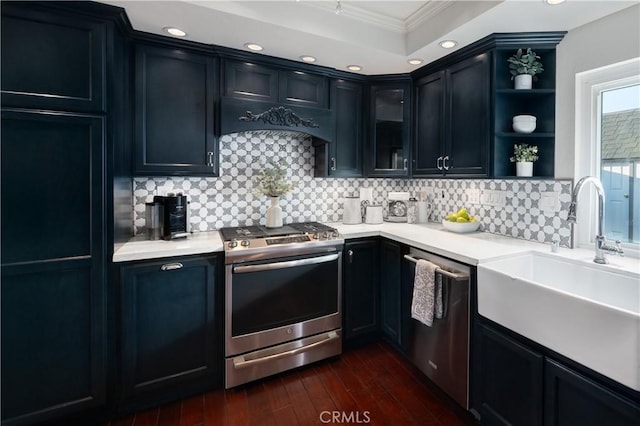 kitchen with dark wood-style flooring, stainless steel appliances, tasteful backsplash, light countertops, and a sink