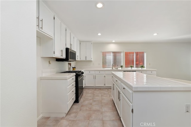 kitchen with range with gas stovetop, recessed lighting, stainless steel microwave, white cabinets, and a sink