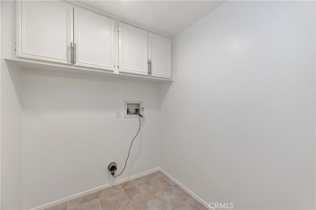 laundry area featuring light tile patterned floors, washer hookup, cabinet space, and baseboards