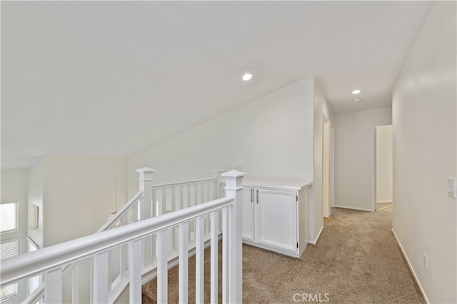 corridor featuring light carpet, baseboards, an upstairs landing, and recessed lighting