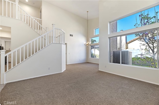 unfurnished living room featuring carpet, a notable chandelier, visible vents, stairway, and baseboards