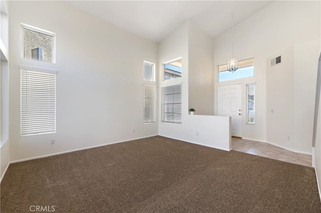 spare room featuring carpet floors, visible vents, high vaulted ceiling, and baseboards