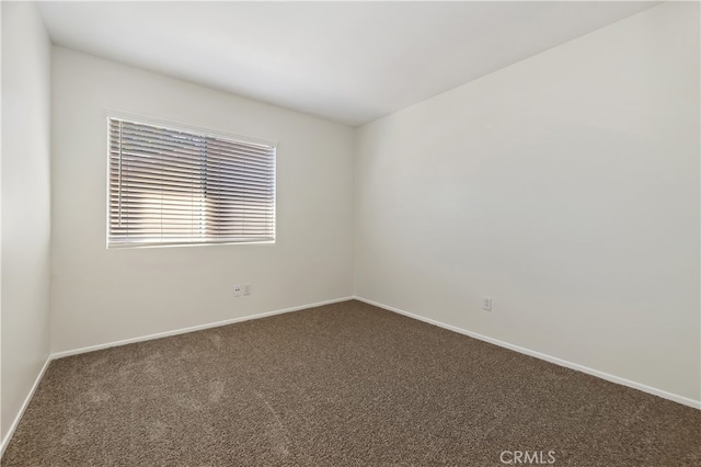 empty room featuring dark carpet and baseboards