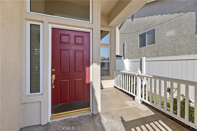 view of exterior entry featuring a porch and stucco siding