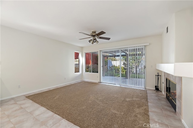 unfurnished living room featuring a fireplace, light tile patterned floors, light colored carpet, a ceiling fan, and baseboards