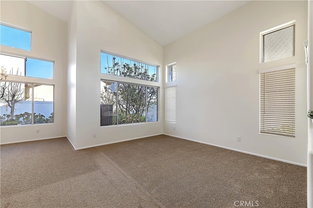 unfurnished room with high vaulted ceiling, dark colored carpet, and baseboards