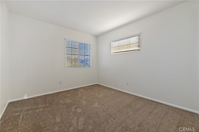 carpeted empty room featuring baseboards