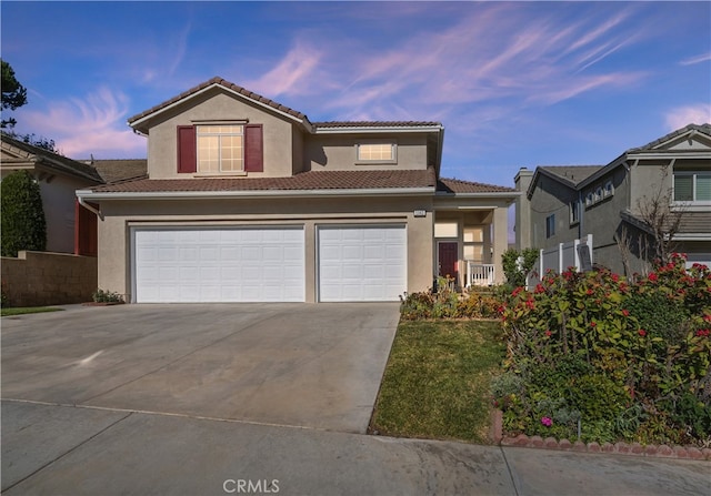 view of front facade with a garage, a tile roof, concrete driveway, and stucco siding